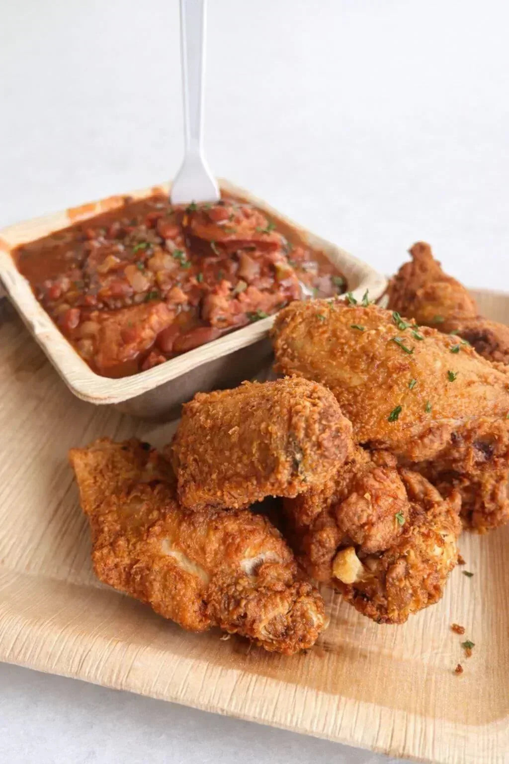 Fried chicken on a wooden plate with a side of dipping sauce - Jerk Fry City