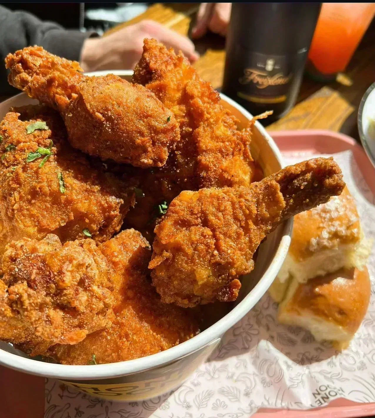 Bowl of fried chicken with a bun on a table