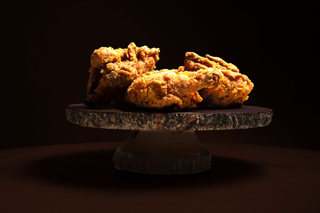 Fried chicken on a dark pedestal against a black background