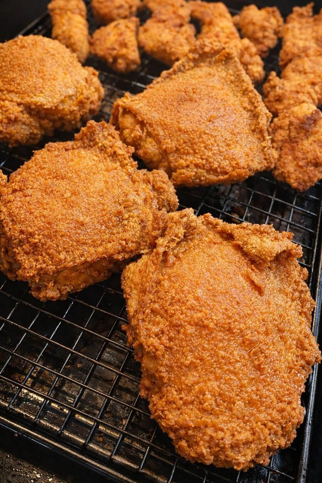 Fried chicken pieces on a cooling rack - Jerk Fry City