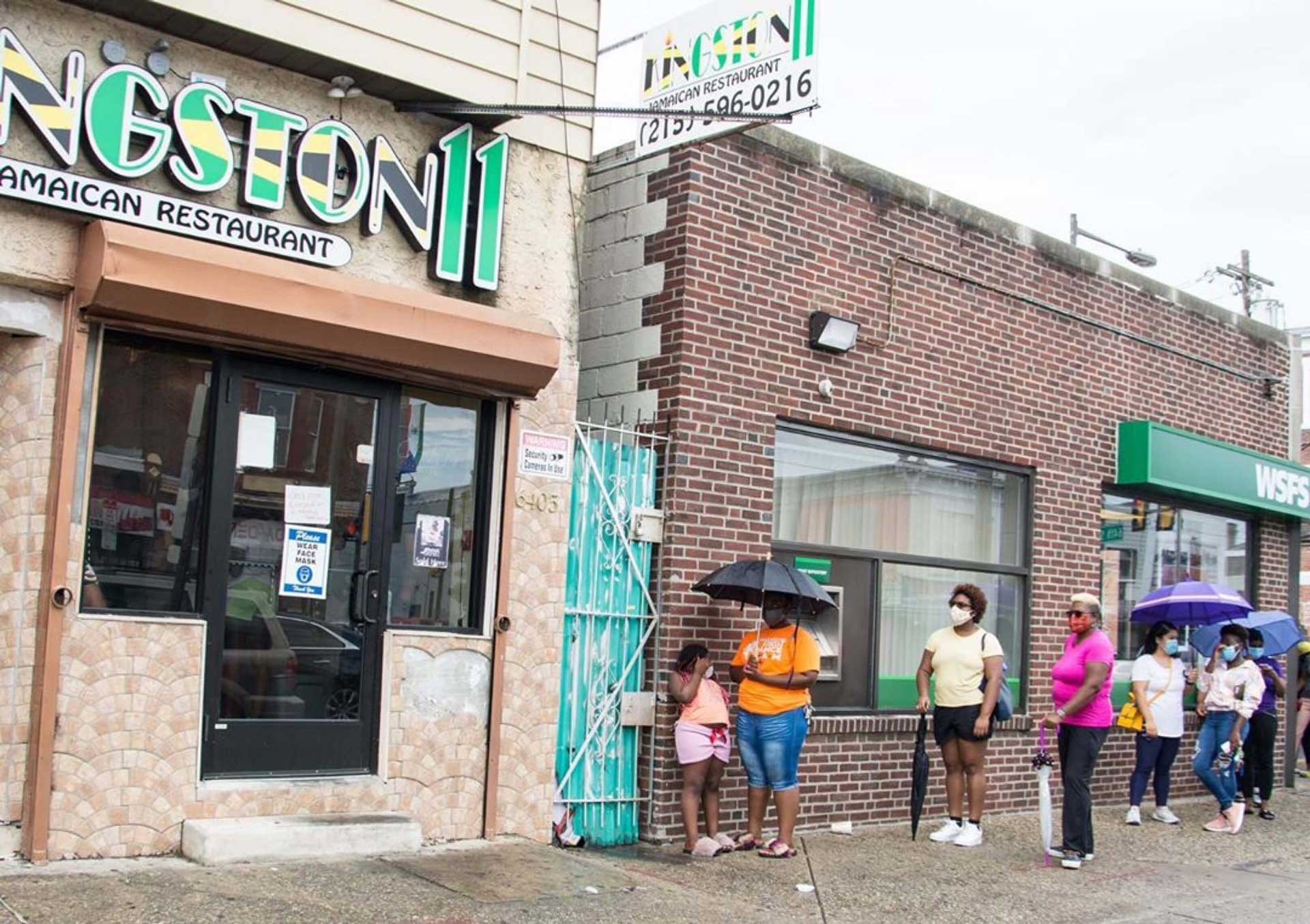 People waiting outside a restaurant with umbrellas on a rainy day Jerk Fry City