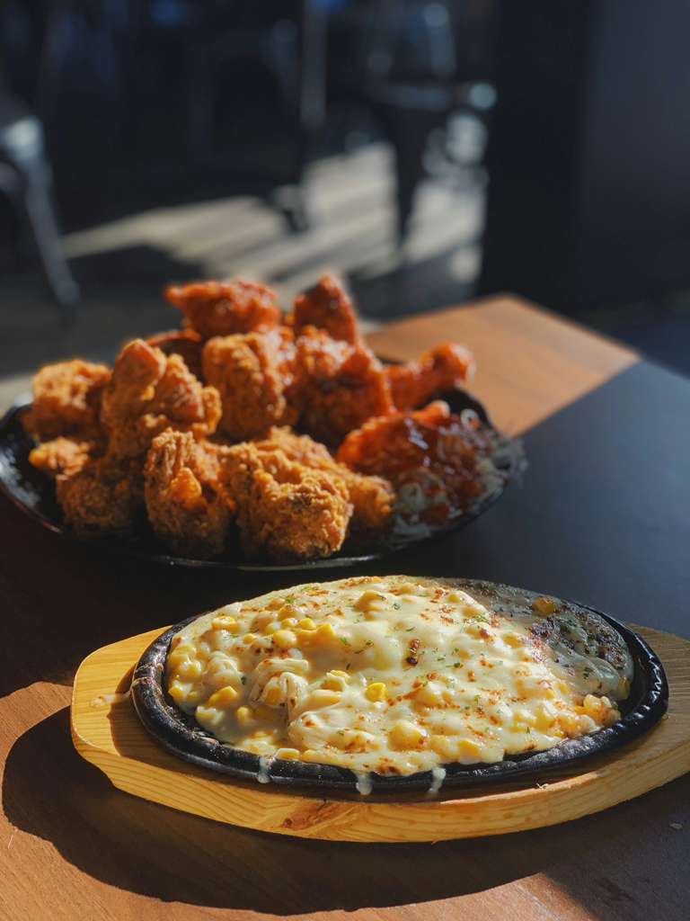 Platter of fried chicken and a small pizza on a wooden board with a blurred background -Jerk Fry City