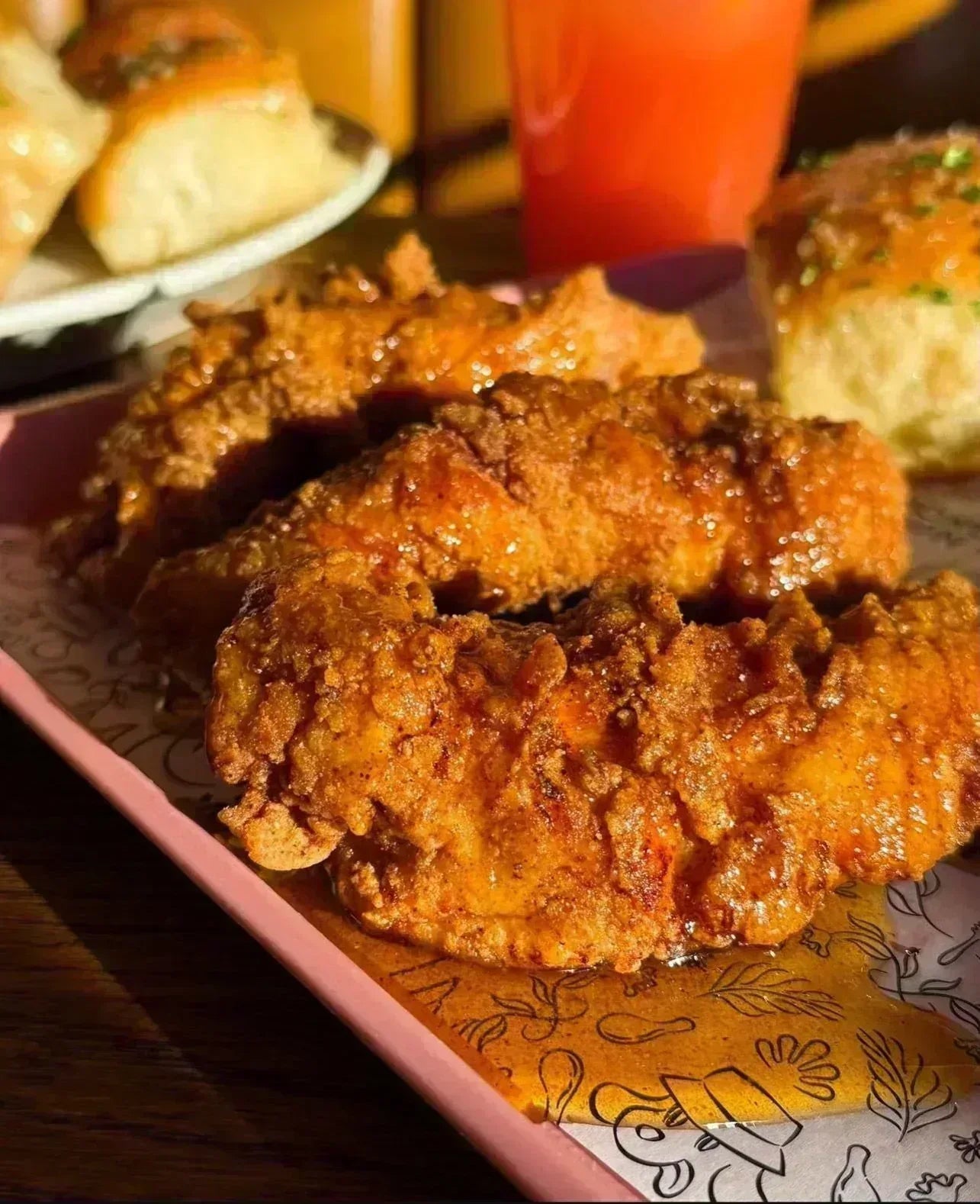 Fried chicken on a decorative plate with a drink in the background